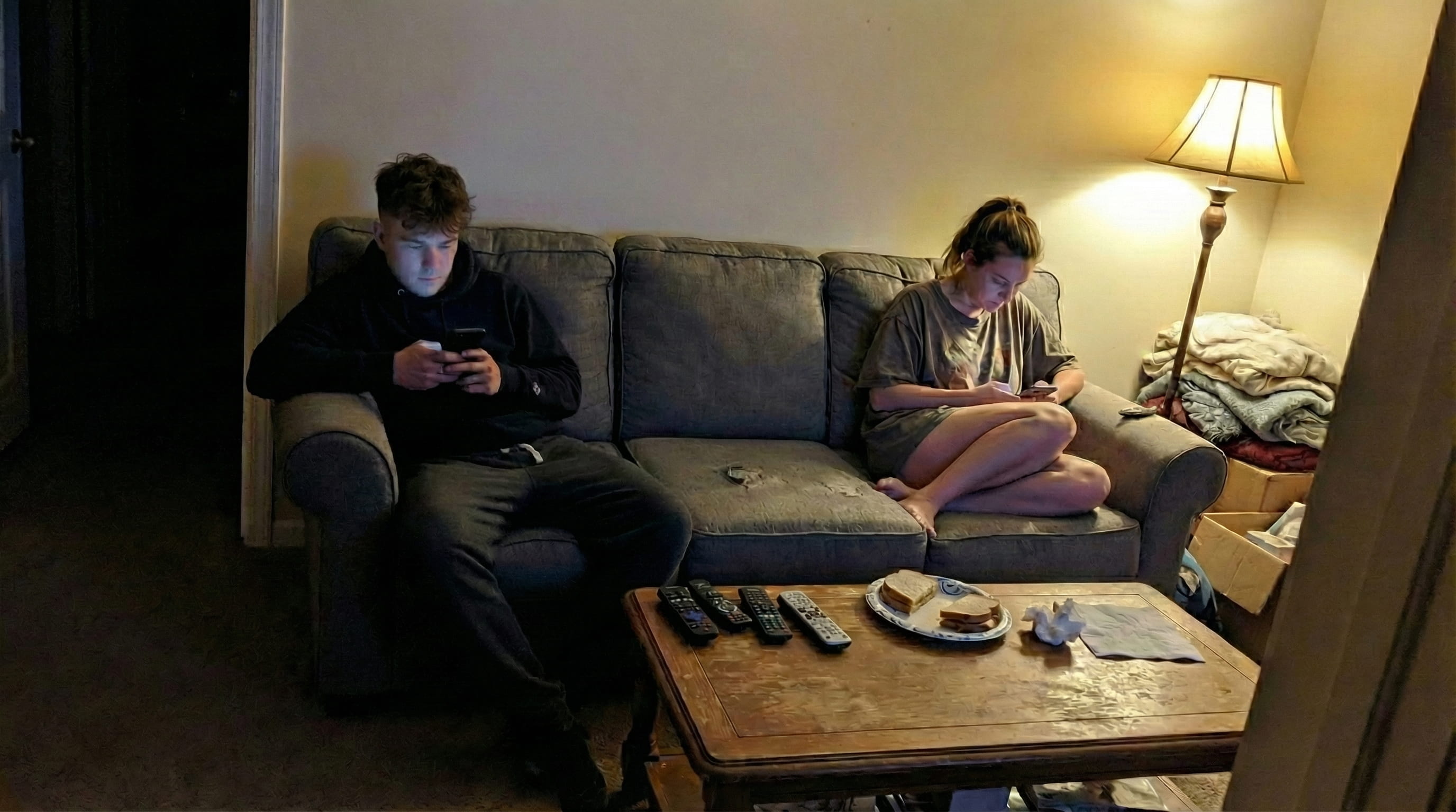 Couple sitting on opposite sides of a couch, each looking at their phones